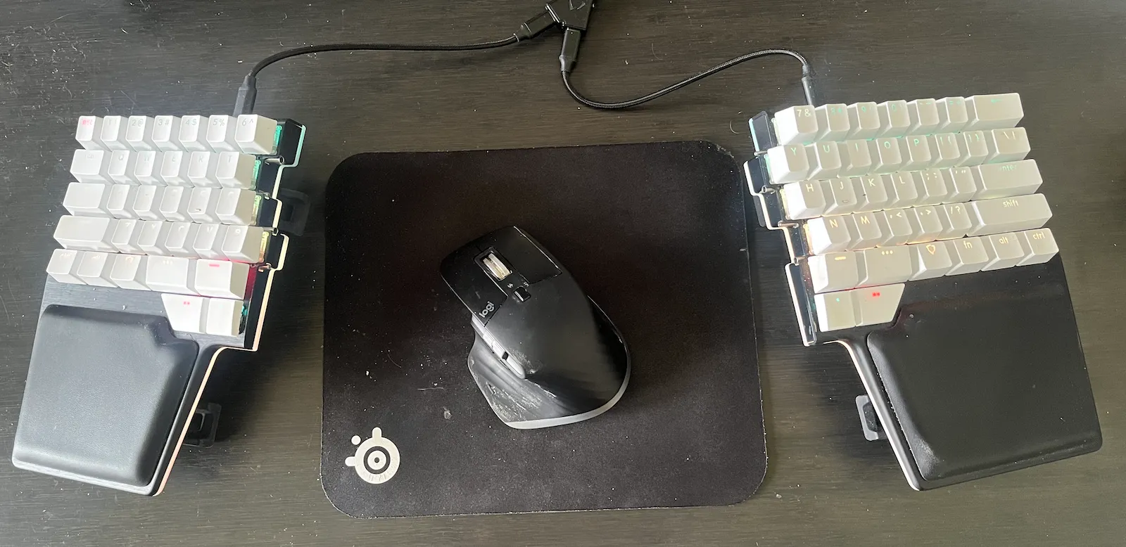 My Dygma Raise keyboard setup with my mouse between the two halves of the keyboard.